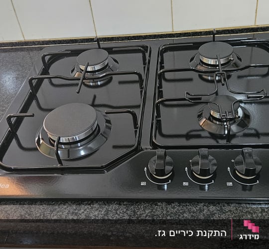 כיריים גז שחורות עם ארבעה מבערים וכפתורי שליטה